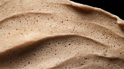Obraz premium Close-up of a textured, porous, light brown surface with dark specks.