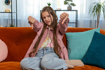 Dislike. Upset girl child showing thumbs down sign gesture, expressing discontent, disapproval,...