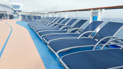 A serene view of blue deck chairs perfectly arranged in neat rows on a luxurious cruise ship deck.