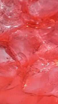 slow motion of ice cubes in cold red cocktail drink. beverage closeup, macro