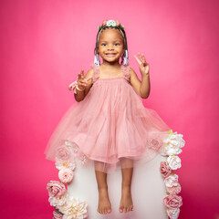 Little girl in pink fluffy dress with pink backdrop