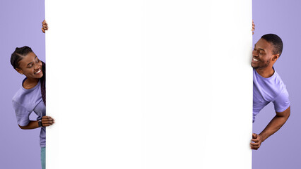 Smiling young black people holding white vertical advertisement board, demonstrating free copy...