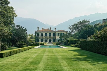 Fototapeta premium Stunning Italian villa surrounded by lush gardens and mountains, featuring a serene pool in the foreground, captured in bright daylight with clear skies