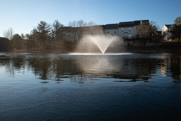 Early winter morning sun over frozen pond with water fountain in Ashburn, Virginia, USA