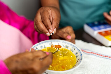 Nurse adding medication to elderly woman's soup for easy administration