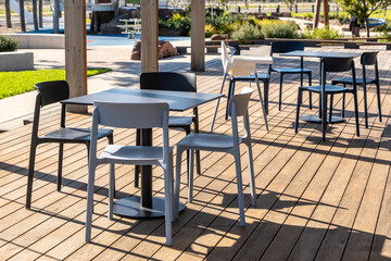 This inviting outdoor seating area features modern tables and chairs arranged on a wooden deck....