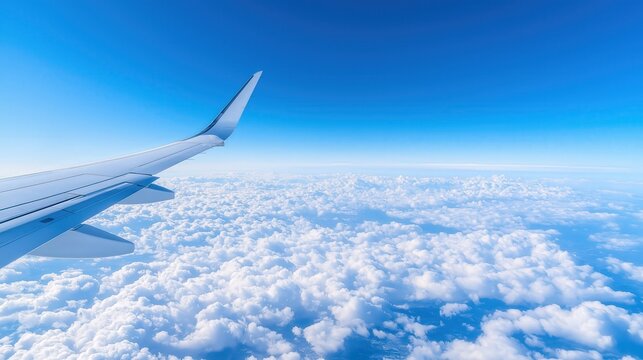 Wing of aircraft soaring above fluffy clouds. Ideal for travel, aviation, vacation, and freedom-themed visuals.