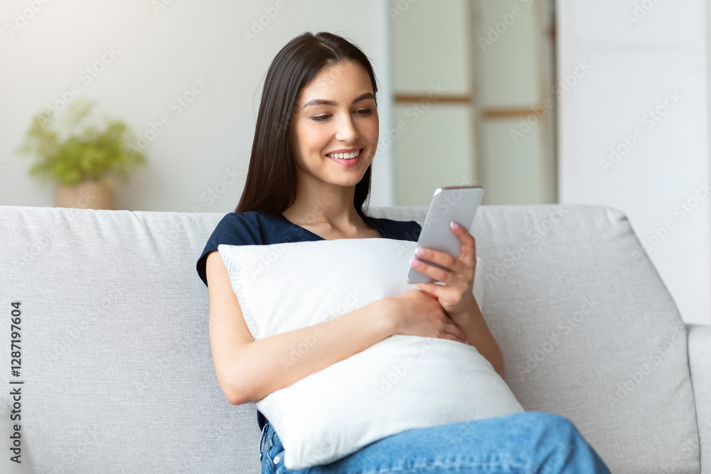 Poster happy girl using mobile phone application, texting and browsing internet sitting on couch at home. f