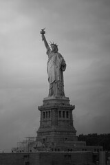 Black and white photo of the Statue of Liberty in New York City, with a cloudy sky in the background.