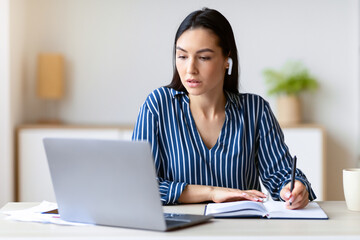 Woman At Laptop Taking Notes Combining Work And Study Learning Sitting In Modern Office. Business Career. Selective Focus