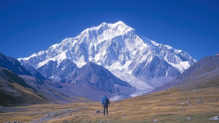 Hiker exploring snowy mountain peak against clear blue sky
