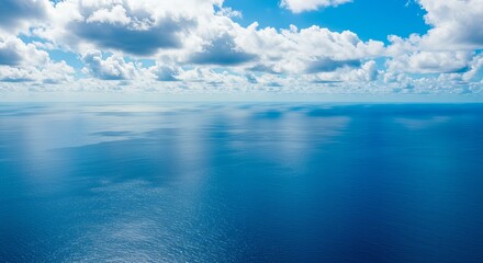 Fototapeta premium Tranquil ocean horizon under bright blue sky with fluffy clouds