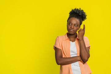 African American woman touches temple with finger, showing deep thought and focused expression....
