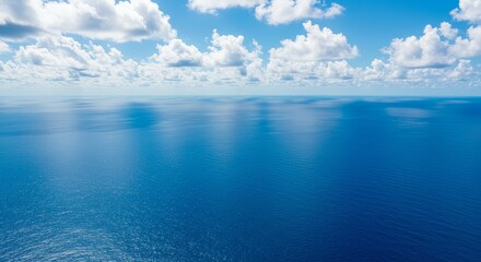 Obraz premium Tranquil ocean view with blue sky and fluffy clouds reflecting on calm waters