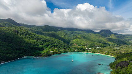 Bay with turquoise waters, mountains in the background, and green hillsides. Seychelles, Mahe.