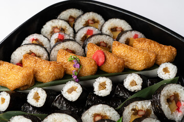 Close-Up of Sushi Rolls and Inari: A Platter Showcasing a Colorful Array of Maki Rolls with Various Fillings, Complemented by Flavorful Inari Sushi Pockets, Highlighting the Variety and Appeal of Japa