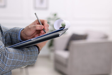 Real estate appraisal. Inspector with clipboard conducting property valuation indoors, closeup....