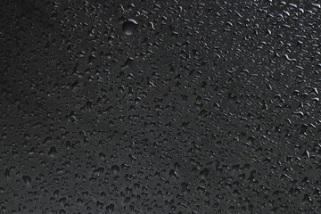 Water drops on dark grey glass surface, top view
