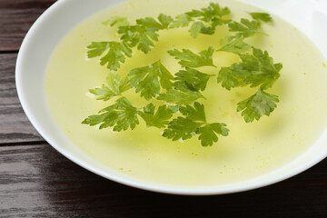 Tasty chicken bouillon in bowl on wooden table, closeup