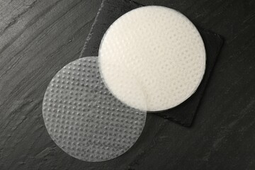Edible rice paper sheets on dark textured table, top view