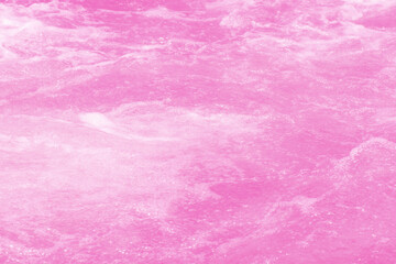 Pink water bubbles on the surface ripples. Defocus blurred transparent pink colored clear calm water surface texture with splash and bubbles. Water waves with shining pattern texture background