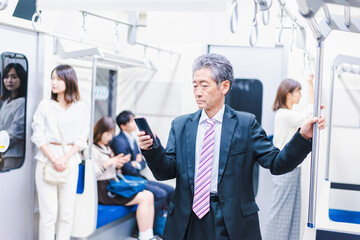 電車内でメールを送るビジネスマン