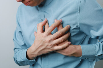 heart disease concept. man pressing on chest with painful expression. severe heartache and having heart attack or painful cramps..