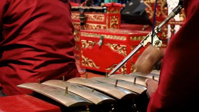 A professional saron player plays the saron one of the gamelan instruments in a wayang performance