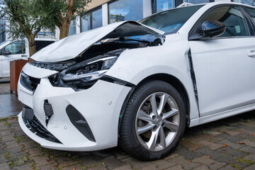 front white crashed car close up, badly damaged car after car accident, huge dent in car body, reckless driving, insurance reminder