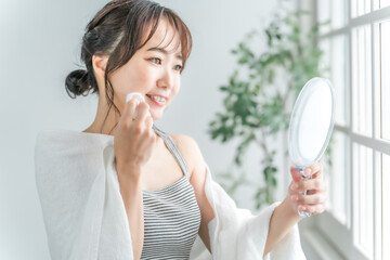 コットンで化粧水を肌につけるアジア人女性
