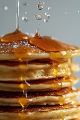 Golden syrup cascade over fluffy pancake stack creating a delicious breakfast indulgence