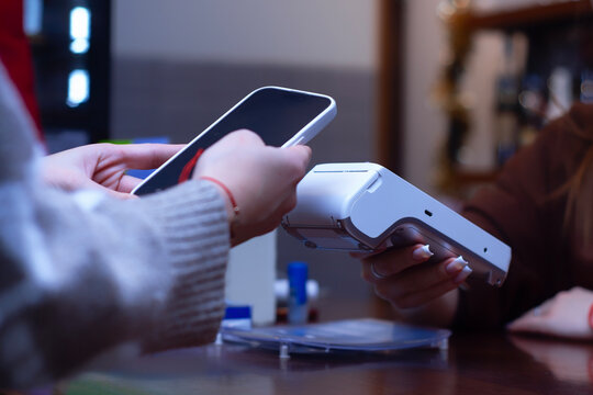 Close-up of a customer making a contactless payment with a smartphone at a point-of-sale terminal.