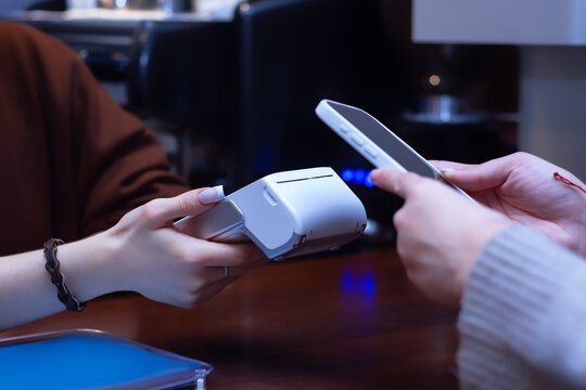 Close-up of a customer making a contactless payment with a smartphone at a point-of-sale terminal.