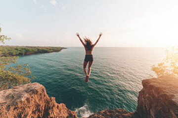 A woman is jumping into the ocean from a cliff