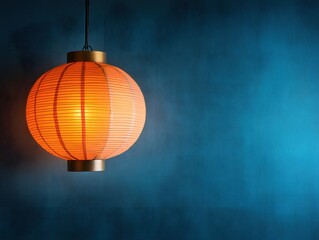 Obraz premium Glowing orange paper lantern casting a warm light against a textured deep blue backdrop