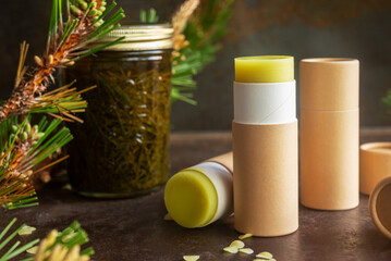 homemade pine needle salve in paper tube on brown rustic background.