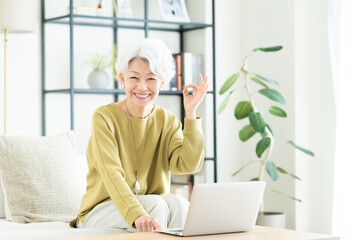 リビングでパソコンを使うシニアの女性