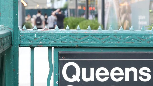 New York subway sign, Queens underground metro station. Metropolitan entrance fence, public transport exit. Long Island city street, NYC United States. Navigation text on signboard. Pedestrians people