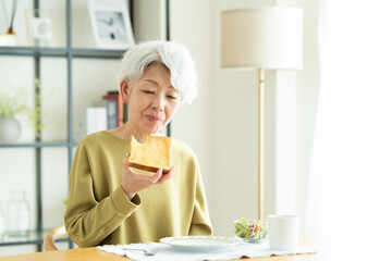 朝食で食パンを食べるシニアの女性