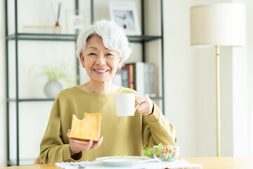 朝食で食パンを食べるシニアの女性