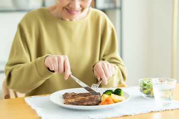ステーキを食べるシニアの女性