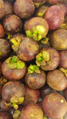 Close-up of a bunch of fresh mangosteens, showing their bright purple skin and green caps. Close-Up of fresh mangosteen background texture material.is a display in supermarket