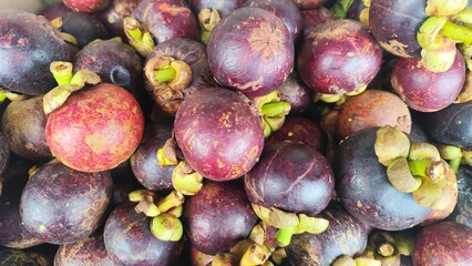 Close-up of a bunch of fresh mangosteens, showing their bright purple skin and green caps. Close-Up of fresh mangosteen background texture material.is a display in supermarket