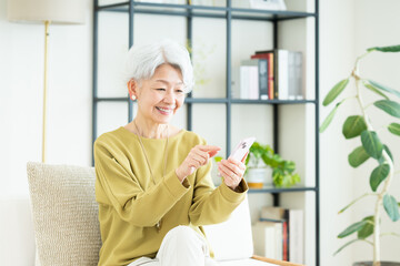 リビングでスマホを使うシニアの女性