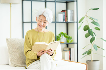 リビングで読書をするシニアの女性
