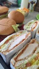 Close-up of two sandwiches with bacon, salami, prosciutto and fresh vegetables on rustic wooden cutting board. Club sandwich concept