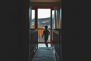Fototapeta premium A child is standing in a hallway with a view of the mountains