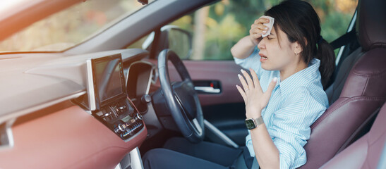woman driving car with broken air conditioner in hot summer weather, uses tissue paper napkin to...