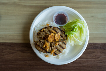 Delicious hamburger steak served on rice in a paper plate. A creative fusion food