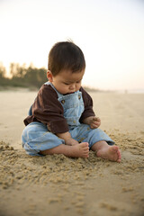 there is a baby sitting on the sand on the beach